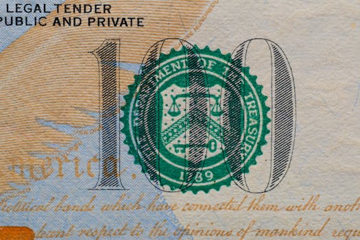Detailed view of the US 100 dollar bill showing the Treasury seal and printed text.